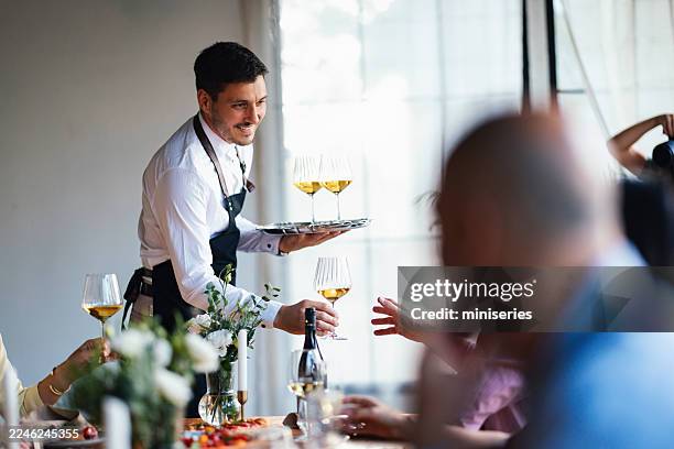 waiter serves wine to friends during elegant lunch celebration - foodservice stockfoto's en -beelden