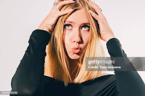 playful blonde with hands in hair making a kissy face, wearing a black top, ideal for fashion, lifestyle, and social media campaigns - comedian stock pictures, royalty-free photos & images