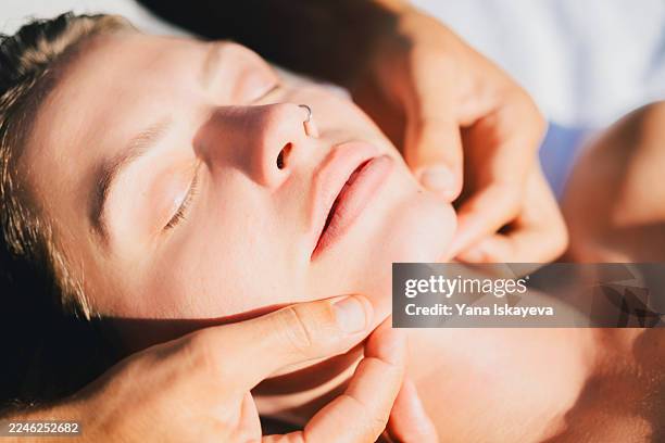 relaxing facial massage during spa treatment with gentle hands and calm, peaceful expression - lymphatic system stock pictures, royalty-free photos & images