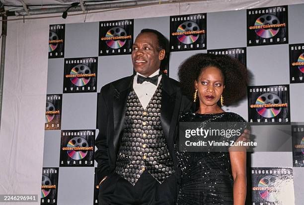 American actor Danny Glover, wearing a tuxedo over a patterned waistcoat and a white shirt with a black bow tie, and American actress Alfre Woodard,...
