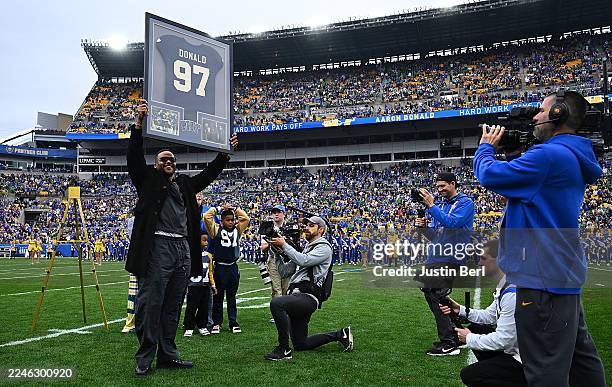 Former Pittsburgh Panthers player Aaron Donald shows off a framed jersey during his jersey retirement ceremony at halftime of the game between the...