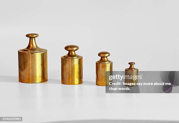 four bronze weights of varying sizes and weights on a white background. the history of weights is, in essence, humanity's continuous quest for precision and universality in measurements. - kilogram stock pictures, royalty-free photos & images