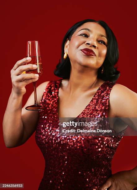 selbstbewusste frau mit rotem paillettenkleid mit champagnerglas feiernd - paillettenkleid stock-fotos und bilder