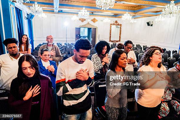 groupe diversifié de fidèles priant ensemble à l’église - bénédiction photos et images de collection