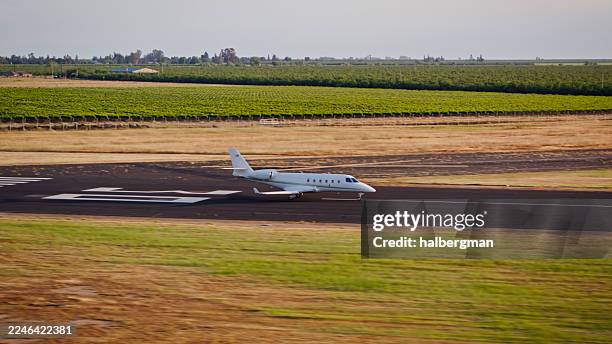 vue latérale d’un jet privé roulant sur la piste de l’aéroport avec arbres et vignobles en arrière-plan - aircraft engine side view photos et images de collection