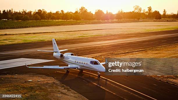 golden hour photo of private jet on airport tarmac with trees and vineyards behind - general aviation stock pictures, royalty-free photos & images