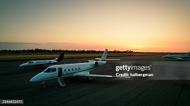 magnifique coucher de soleil derrière une vue latérale de jets privés alignés sur le tarmac de l’aérodrome - prise de vue par drone - aircraft engine side view photos et images de collection