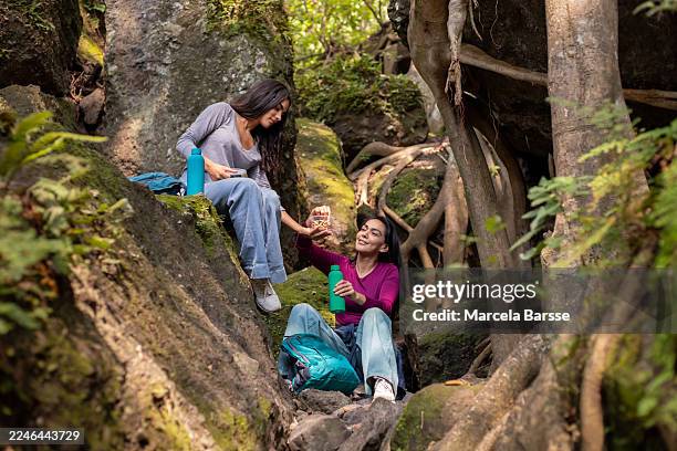 mother and daughter sharing a light snack while resting on a nature hike - trail mix stock pictures, royalty-free photos & images