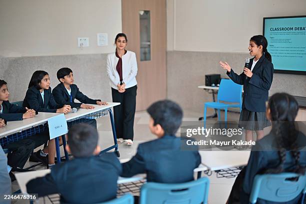 student moderator leads classroom debate between two teams - debat stockfoto's en -beelden