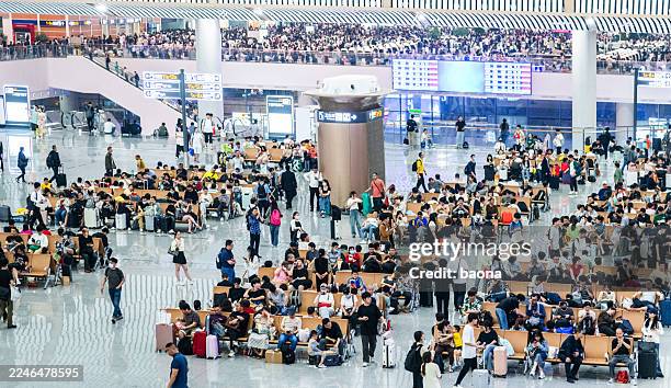 blick aus der vogelperspektive auf viele passagiere, die auf den sitzen sitzen und im abflugbereich warten - flugpassagier stock-fotos und bilder