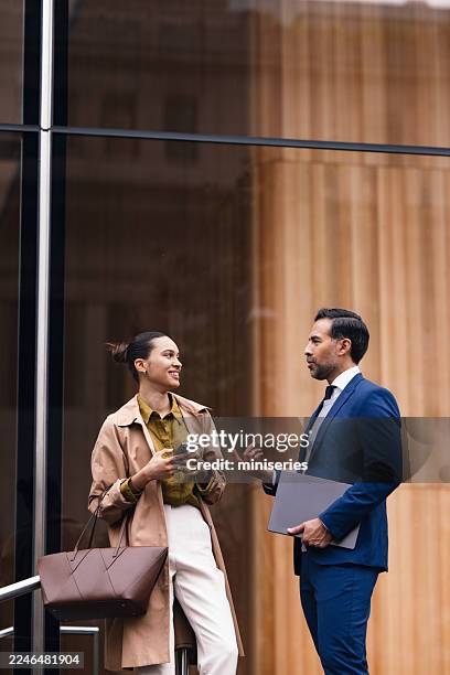 professional conversation between businesswoman and businessman outside modern building in nyc during a networking break - small office stock pictures, royalty-free photos & images