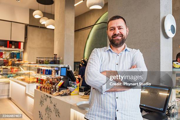 propriétaire de café confiant debout à l’intérieur d’un café moderne - aplatir la courbe photos et images de collection