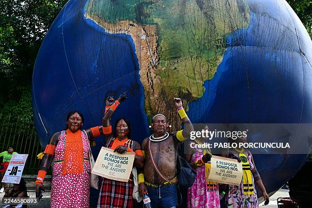 Indigenous people pose next to a giant inflatable globe during the "Indigenous People Global March" at the COP30 UN Climate Change Conference in...