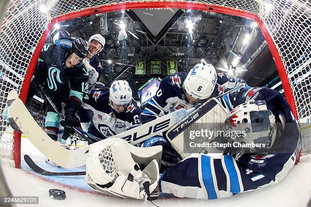Tye Kartye of the Seattle Kraken, Gustav Nyquist, Logan Stanley, Colin Miller and Connor Hellebuyck of the Winnipeg Jets watch a disallowed goal...