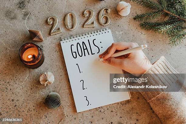 woman's hand writing goals 2026 for new year. new year routine. flat lay style - goede voornemens stockfoto's en -beelden