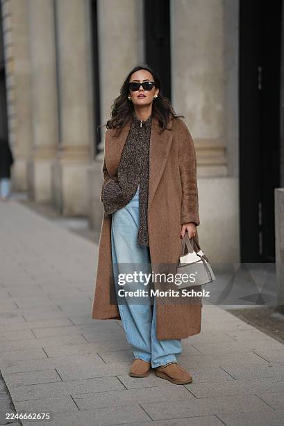 Laura Noltemeyer is seen wearing a long camel-colored brushed wool wrap coat with a belt and wide lapels by Max Mara; a chunky zip-front sweater...