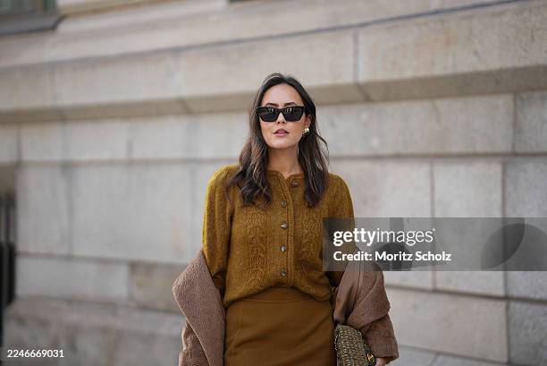 Laura Noltemeyer is seen wearing a a long camel-colored brushed wool coat with a wrap silhouette and integrated belt by Max Mara; a mustard-colored...