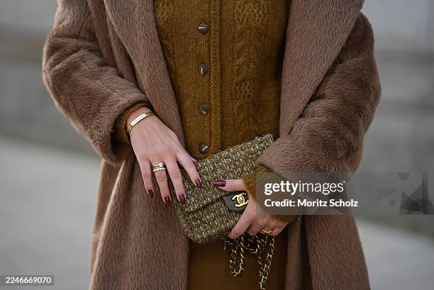 Laura Noltemeyer is seen wearing a a long camel-colored brushed wool coat with a wrap silhouette and integrated belt by Max Mara; a mustard-colored...