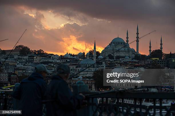 Fishermen are seen on the Galata Bridge at sunset in Istanbul, with the Suleymaniye Mosque in the background.