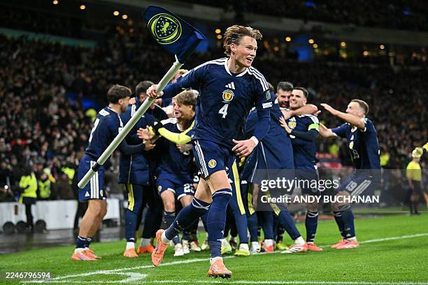 Scotland's midfielder Scott McTominay grabs the corner flag as Scotland's midfielder Kenny McLean celebrates with teammates after scoring his...