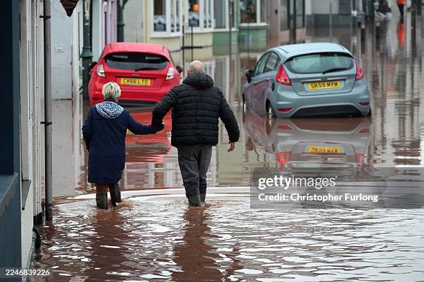 People walk through floodwater on November 15, 2025 in Monmouth, Wales. Storm Claudia caused severe and widespread flooding in Monmouth and has been...
