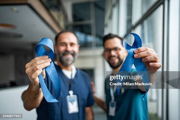healthcare workers holding blue ribbons for prostate cancer awareness - prostate cancer stock pictures, royalty-free photos & images