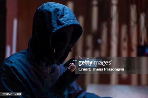 Hacker in dark room coding on multiple screens Hacker in dark room coding on multiple screens