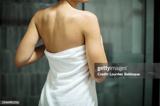 woman wrapped in towel standing in modern bathroom - envuelto en una toalla fotografías e imágenes de stock