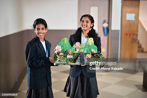 two students proudly present their colorful handmade landscape model/ school project in the school corridor. - school project stock pictures, royalty-free photos & images