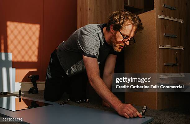 a man assembles flat pack furniture - carpentry stock pictures, royalty-free photos & images