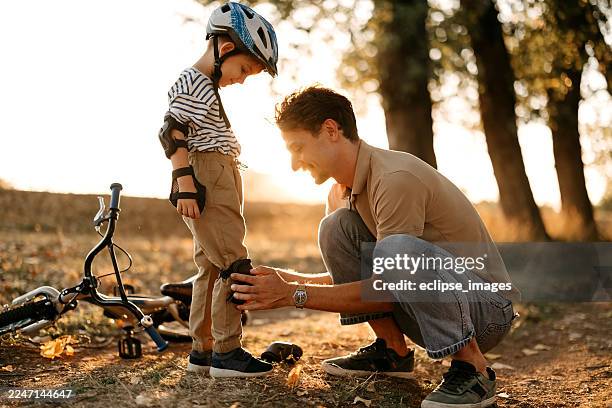 cute little boy getting ready for bicycle ride - cycling helmet stock pictures, royalty-free photos & images