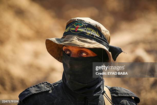 Masked gunman from the Palestinian Islamic Jihad movement keeps watch as others search for bodies in Nuseirat in the central Gaza Strip on November...