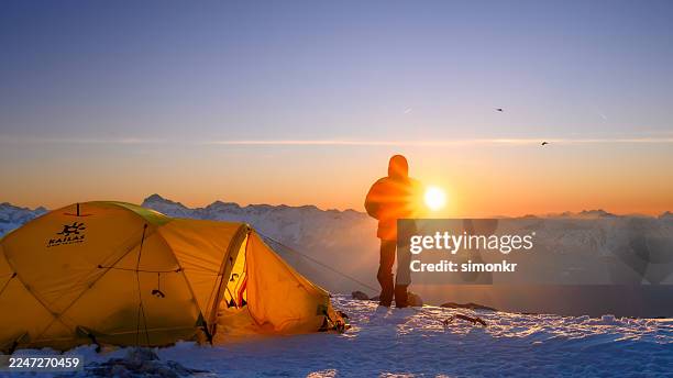 mature caucasian mountaineer admiring sunrise at high mountain base camp with contentment - base camp stock pictures, royalty-free photos & images