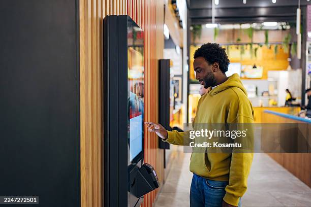hombre negro guapo pidiendo comida en un quiosco de autoservicio - comida rápida fotografías e imágenes de stock