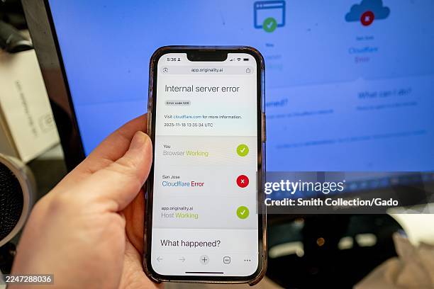 Person's handing hold an iPhone displaying a Cloudflare Error while attempting to access a webpage, during an outage of the Cloudflare service,...