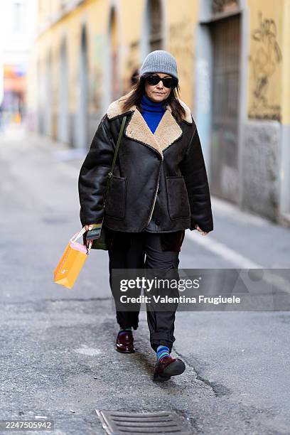 Guest wears a grey beanie, black shearling-lined leather jacket, bright-blue turtleneck, black cargo pants, burgundy loafers and multicoloured...