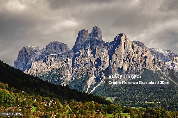 panoramic view of majestic mountains and lush landscape under a cloudy sky,primiero san martino di castrozza,italy,fiera di primiero - primiero foto e immagini stock