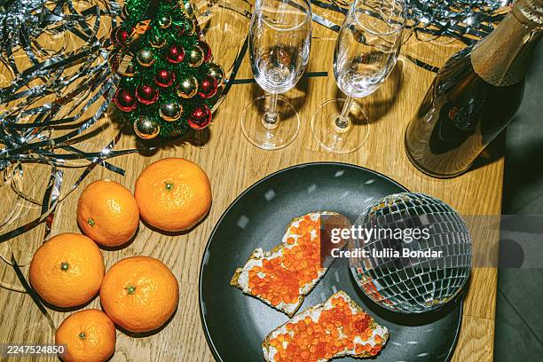 holiday table with mandarins, caviar sandwiches, champagne glasses, and tinsel - red caviar stock pictures, royalty-free photos & images