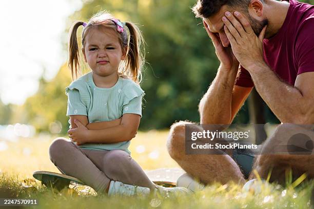 stubborn little girl causing father stress in park - stubborn stock pictures, royalty-free photos & images