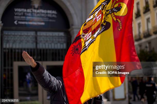Far-right supporter gives the fascist salute and holds a Francoist flag during a rally commemorating the 50th anniversary of the death of dictator...