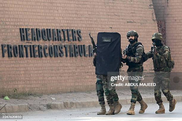 Army personnel take a shield as they move at the suicide bombing site at the border force headquarters in Peshawar on November 24, 2025. A suicide...