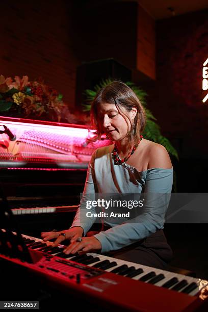 smiling pianist plays keyboard under red neon lights - piano key stock pictures, royalty-free photos & images