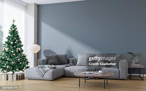 modern living room decorated for christmas, with a large gray sofa, table in front of a gray blank wall, christmas tree in front of large windows with view - french doors stock pictures, royalty-free photos & images