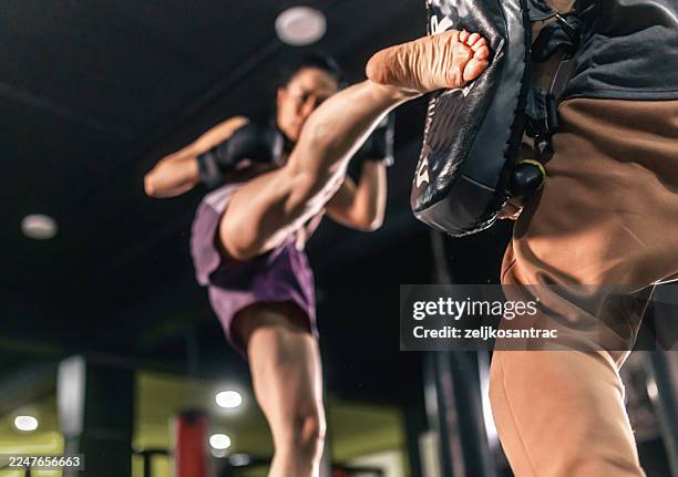 woman practicing kickboxing during intense sparring session - kickboxing stock pictures, royalty-free photos & images
