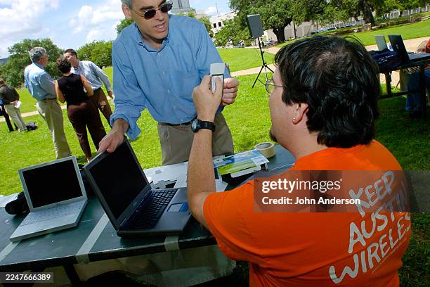 Community activist Chris Riley picks up an AT&T Plug & Share Wireless Notebook Adapter from an unidentified Keep Austin Wireless volunteer during a...