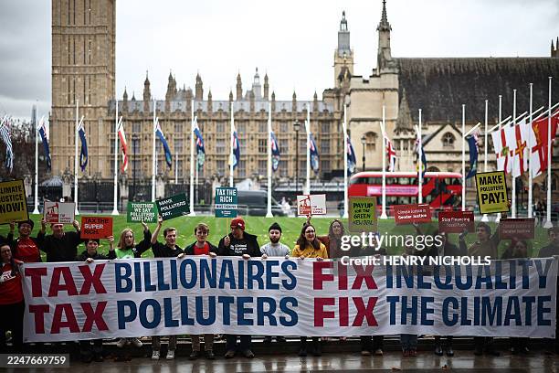 Activists from the 'Make Them Pay' and 'Make Polluters Pay' coalitions hold a banner reading 'Tax Billionaires; Fix Inequality; Tax Polluters; Fix...