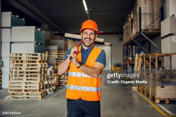 happy warehouse worker smiling carrying broom - broom stock pictures, royalty-free photos & images