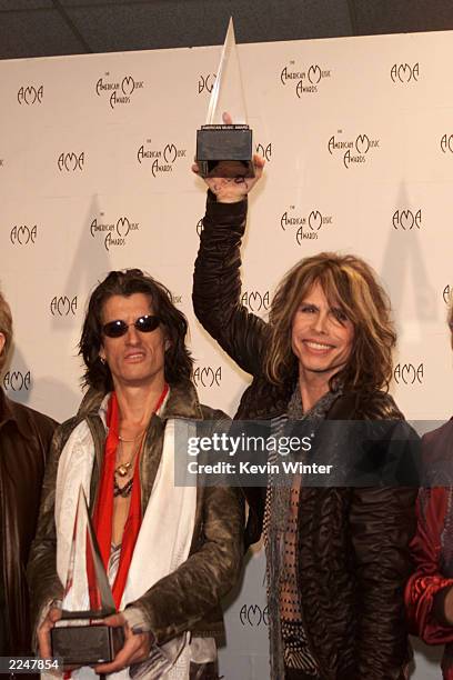 Steven Tyler of Aerosmith holds up award as Joe Perry looks on backstage at the 28th Annual American Music Awards at the Shrine Auditorium in Los...