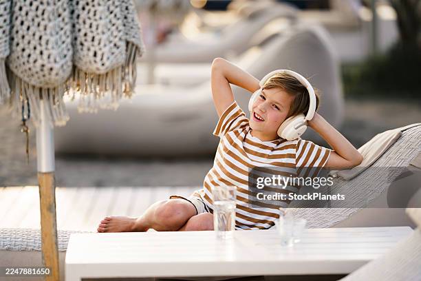 little boy relaxing on lounge chair enjoying music. - barefoot stock pictures, royalty-free photos & images