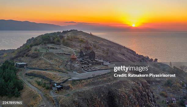 the historic 9th-century sevanavank monastery, an iconic landmark on the shores of lake sevan, armenia, is silhouetted against a spectacular golden sunrise. - sevanavank monastery stock pictures, royalty-free photos & images
